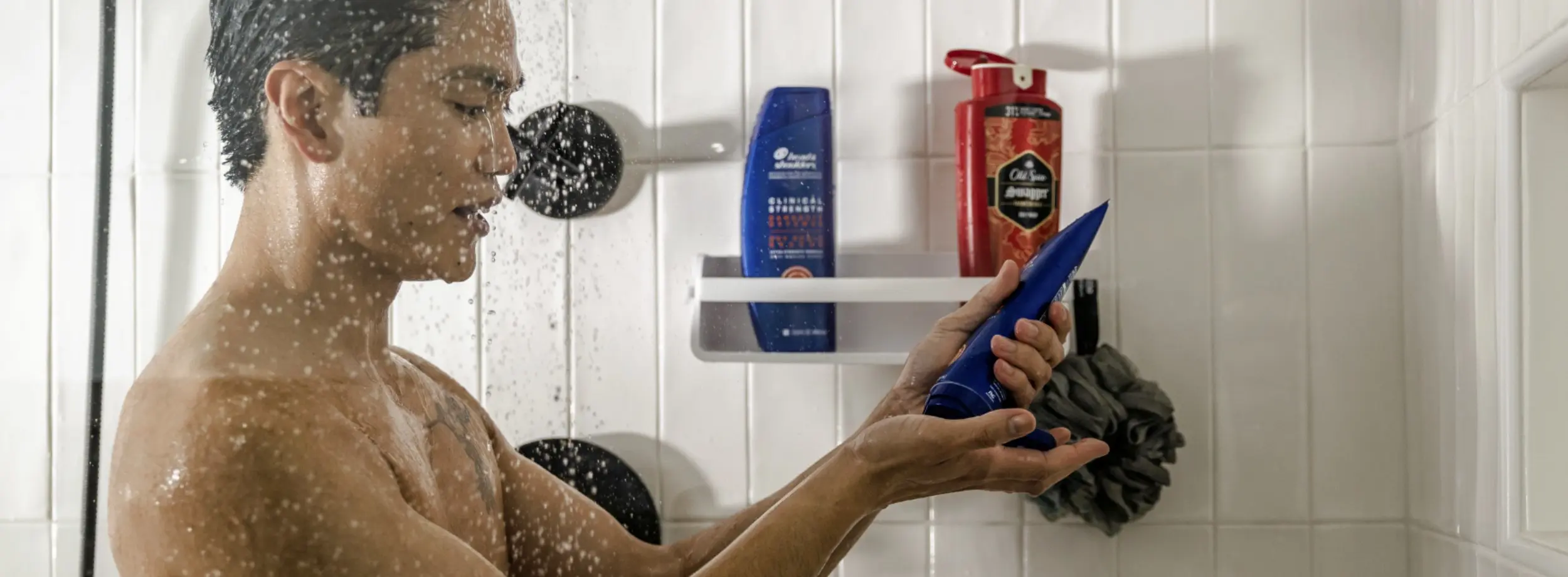 Man in shower squeezes Head & Shoulders shampoo into his hand.